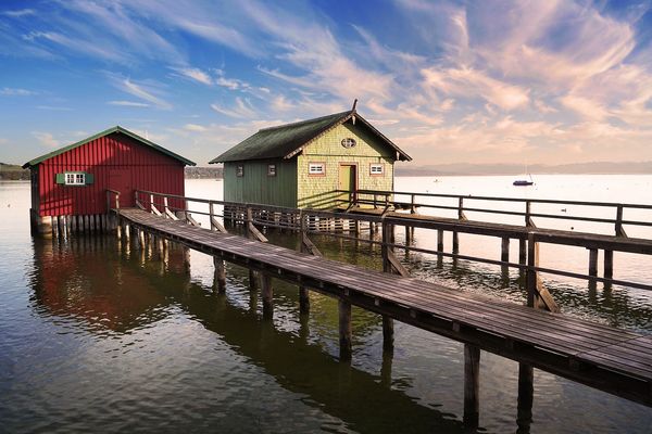 Two colorful boathouses with jetty on the Ammersee near Munich.