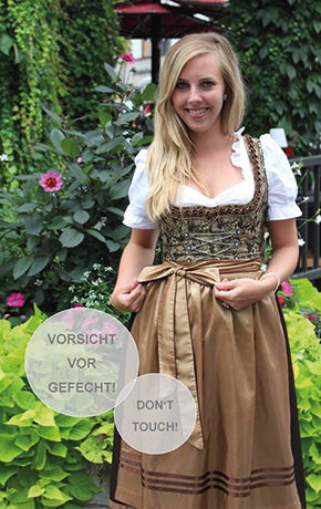 A young women is wearing a typical Bavarian costume outdoor in the green. 