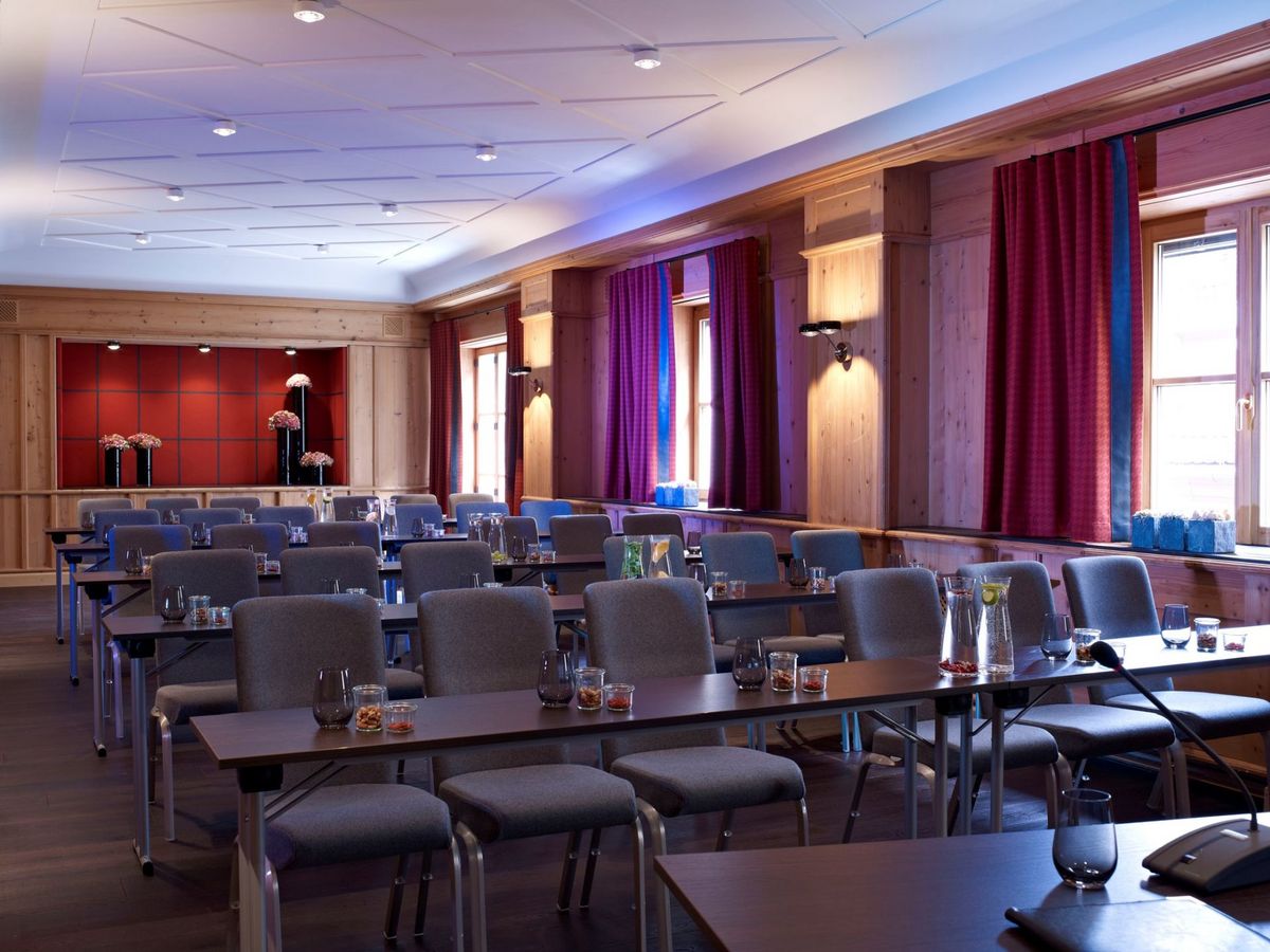 A wooden panelled conference room at the Platzl Hotel Munich with several rows of tables and chairs