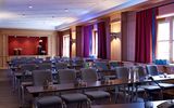 A wooden panelled conference room at the Platzl Hotel Munich with several rows of tables and chairs