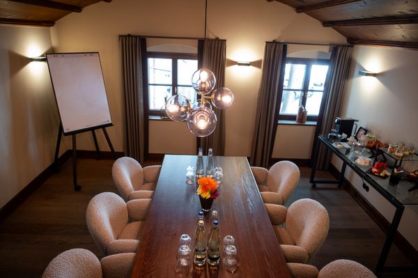 Bright Bäcker Stube with wooden ceiling, large table, eight chairs and daylight windows