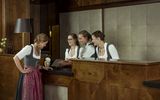 Four female employees of the Platzl Hotel in Munich are standing around the reception of the hotel and talking