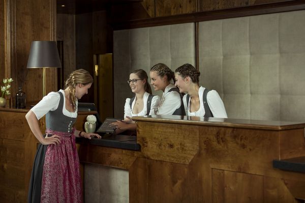 Vier Rezeptionistinnen stehen an der Rezeption des Platzl Hotels München und unterhalten sich
