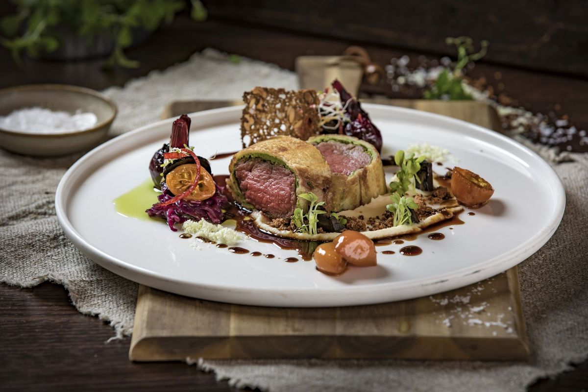 A plate with a fillet of beef and several side dishes on a wooden board at the Platzl Hotel Munich