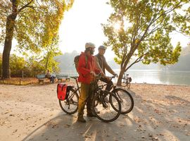Two sporty cyclists in the English Garden Munich in front of a small lake.