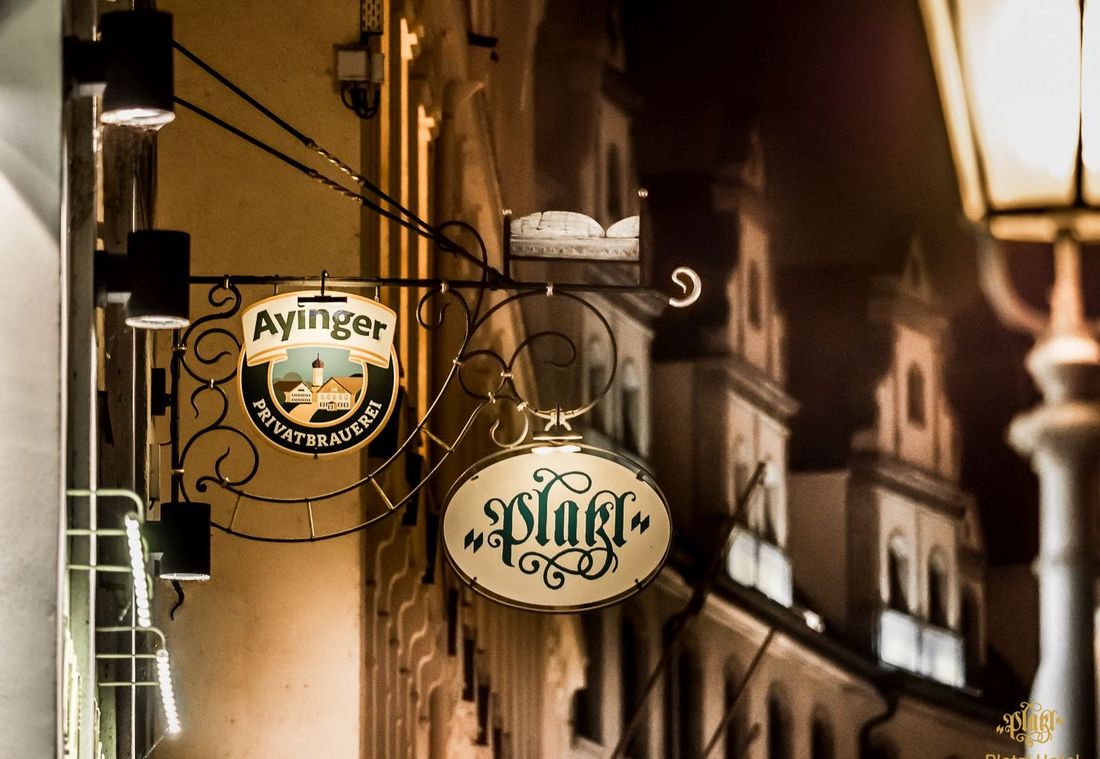 Eine nächtliche Aufnahme des beleuchteten Schilds des Platzl Hotels München