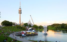 Gutbesuchtes Freiluftkino am Münchener Olympiapark, mit dem See und dem Stadion im Bild.