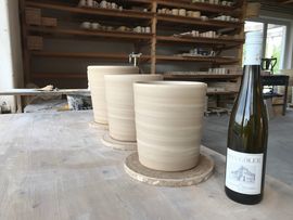 Handmade ceramic wine cooler with wine bottle next to it.