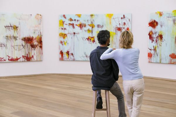 Ein Paar betrachtet moderne abstrakte Kunst in der Pinakothek der Moderne in München und ist von den farbenfrohen Gemälden fasziniert.