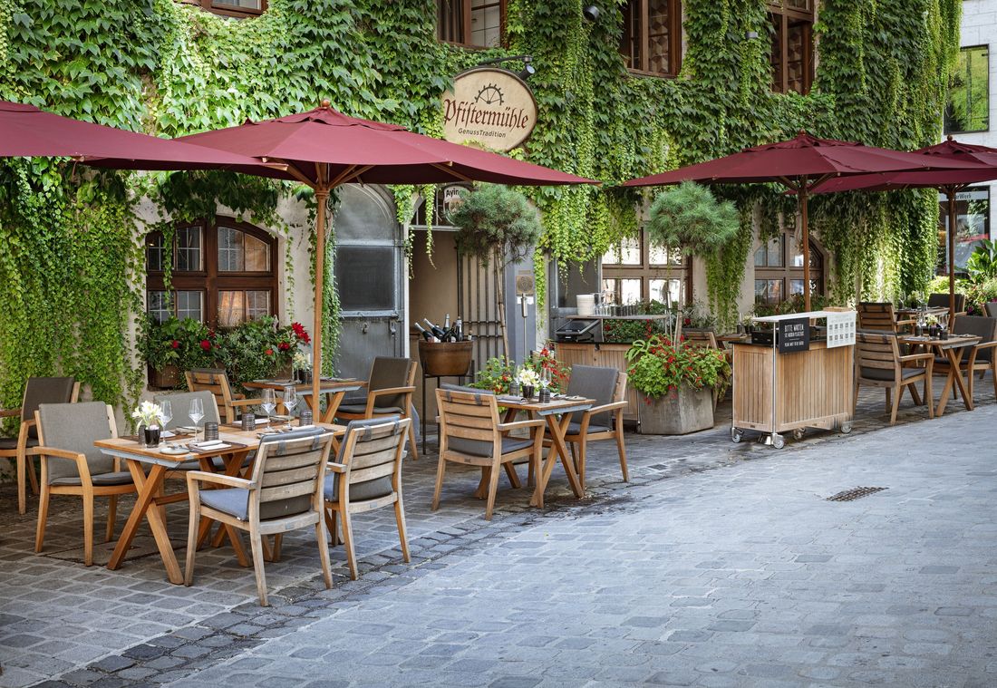 Outdoor tables and chairs stand in front of the ivy-covered Pfistermühle restaurant