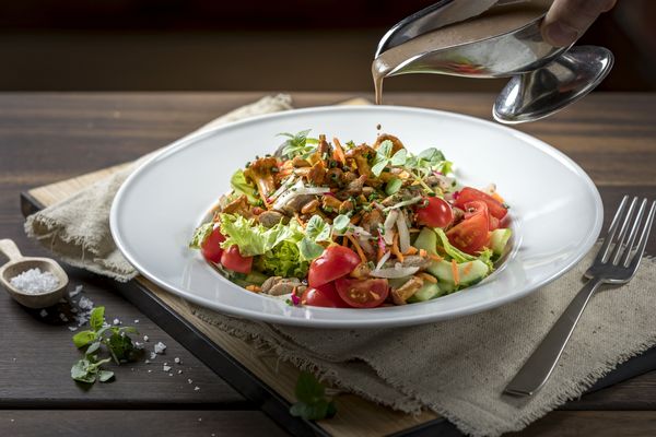 Colourful salad with chanterelles is poured with creamy dressing