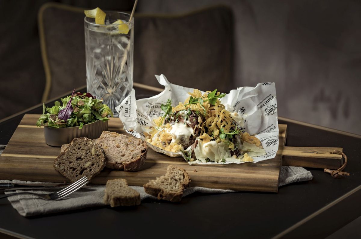 Fine cuisine in the Platzl Hotel Munich: A typical Bavarian dish has been arranged on a wooden board - next to it are several slices of bread