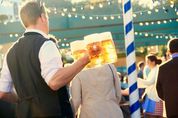 A waiter at the Oktoberfest carries full beer mugs to the guests. 