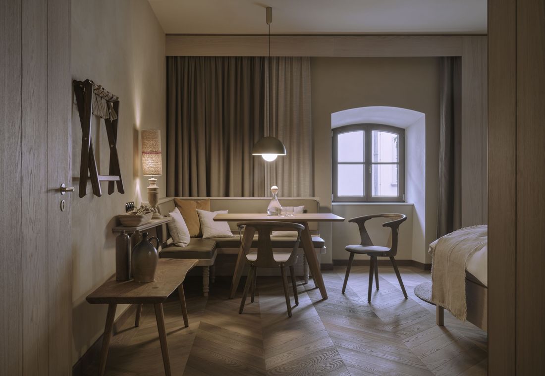 Gemütliche Sitzecke mit Holztisch und Leinenkissen in einer charmanten Suite in München