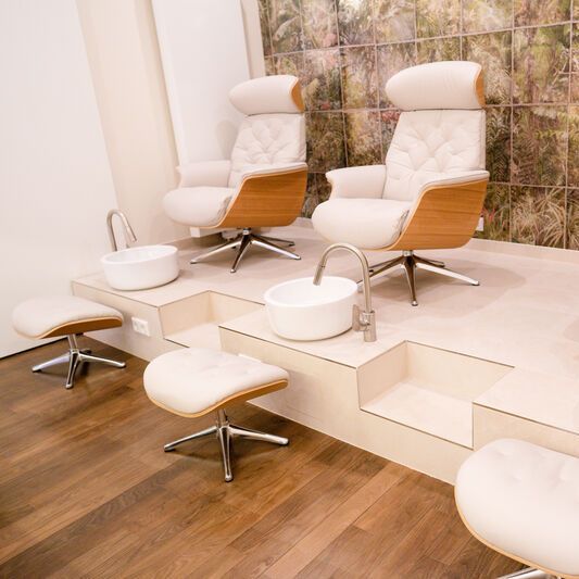 Spa area with two comfortable armchairs, stools and washbasin in each.