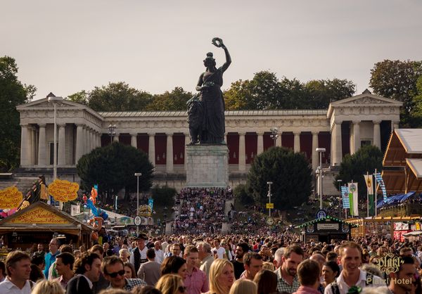 Crowd in front of the Bavaria statue at the Oktoberfest in Munich in daylight.