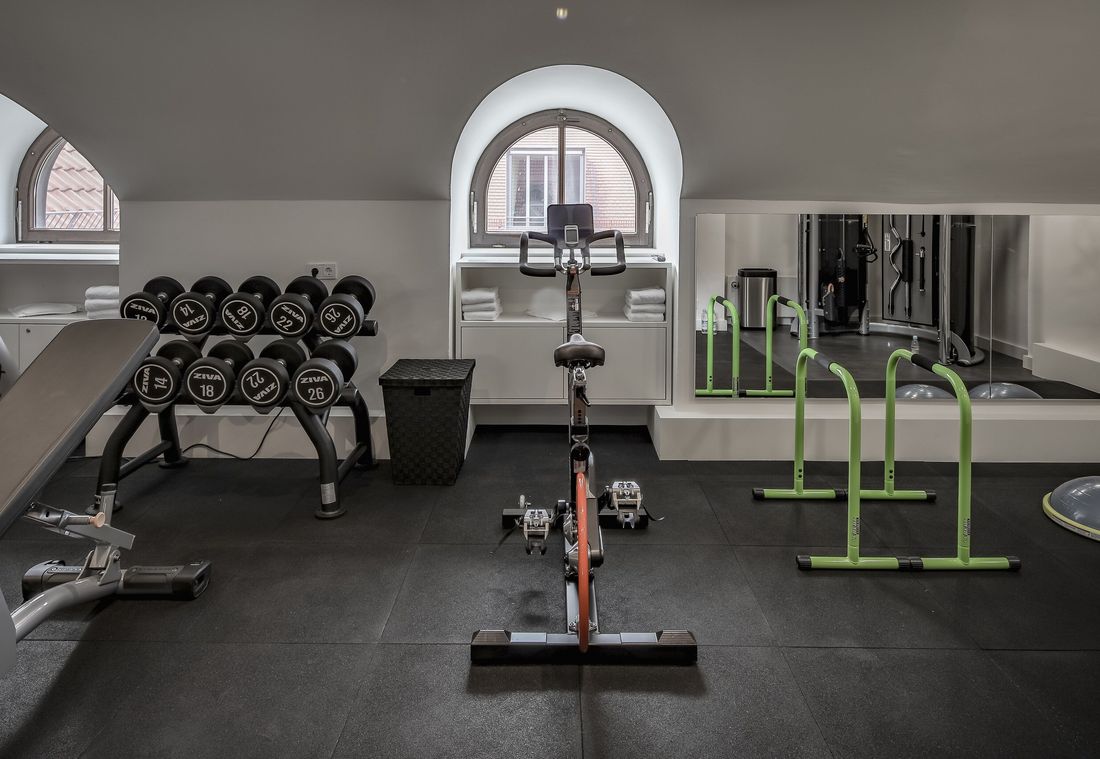 Der moderne Fitnessraum des Hotels bietet ein Spinningrad, Hanteln und viel Tageslicht