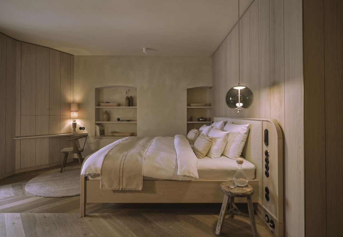 Eine stilvolle Suite in München mit Naturholzboden, Doppelbett und dekorativen Wandnischen
