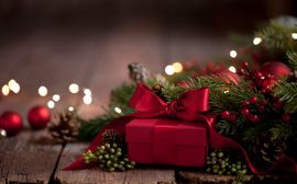 Geschenk Rot eingepacktes Geschenk vor Tannenzweigen und weihnachtlicher Dekoration.