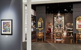 Ausstellungsraum in einer Kunstgalerie mit antiken Möbelstücken, vergoldeten Spiegeln, Kronleuchter und gerahmtem Bild an der grauen Wand im Vordergrund