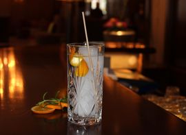 Ein Gin Cocktail im Longdrinkglas mit Orangenschale in der Bar des Platzl Hotel München