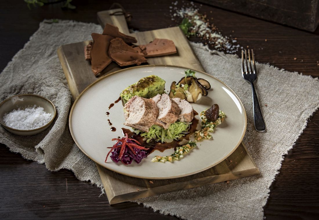 Gourmetgericht mit Hähnchen und Gemüse kreativ angerichtet auf Keramikteller
