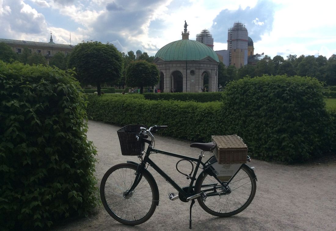 Ein Platzl-Fahrrad mit Weidenkorb steht vor dem Dianatempel im Hofgarten in München