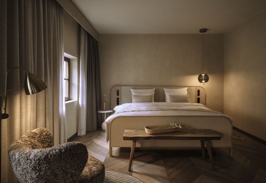 In dieser Suite in München steht ein Doppelbett mit warmem Lichtkonzept in ruhiger Atmosphäre