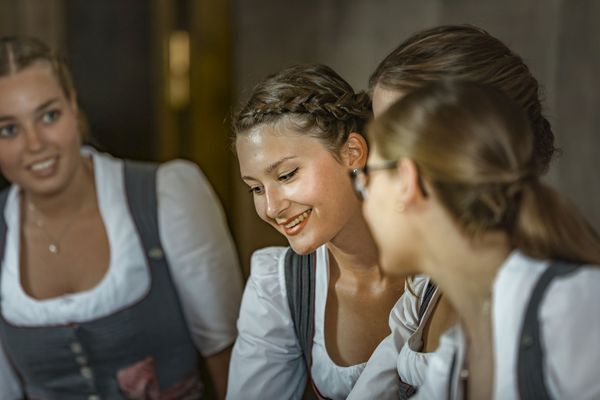 Three receptionists of the Platzl Hotel Munich stand together at the reception