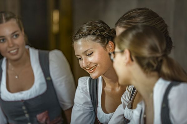 Drei Empfangsmitarbeiterinnen des Platzl Hotels München stehen gemeinsam an der Rezeption