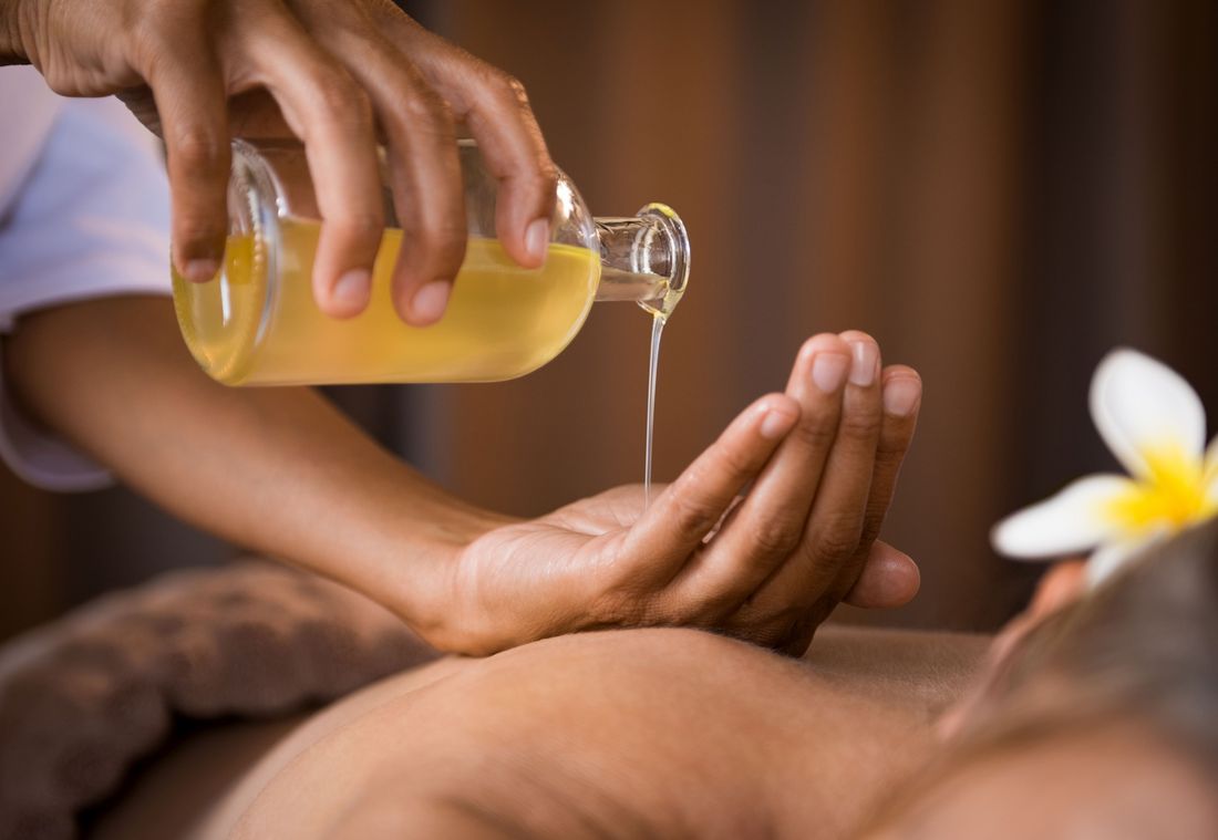 A close-up of oil being poured into hands for a wellness massage treatment