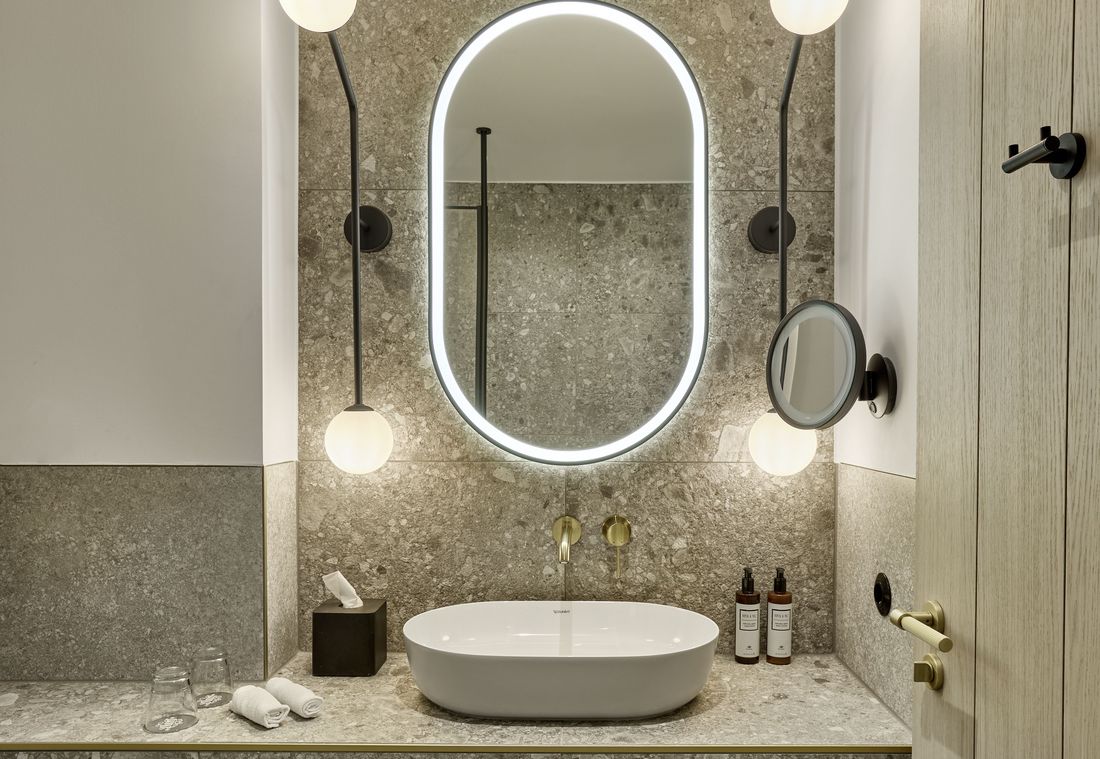 Das moderne Badezimmer besticht durch Naturstein, elegantes Waschbecken und stimmungsvolle Beleuchtung