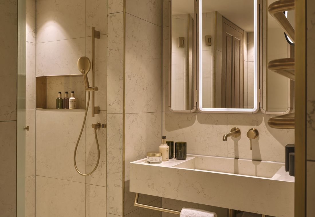 Das moderne Bad der Suite in München ist mit großer Dusche, Doppelwaschbecken und Spiegel ausgestattet