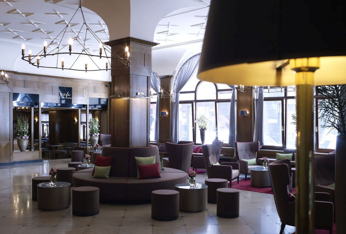 Hotellobby Die großzügige Lobby im Platzl-Hotel München mit verschiedenen Sesseln und einer Sitzbank um eine Säule in der Mitte des Raumes