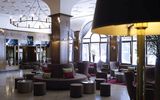 The spacious lobby at the Platzl Hotel Munich with various armchairs and a bench around a column in the middle of the room