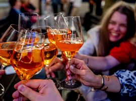 Mehrere Personen stoßen mit Gläsern gefüllt mit Aperol an