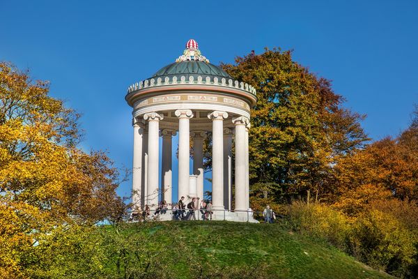Auf einen Hügel gebauter heller Säulenpavillon in einem Park in München