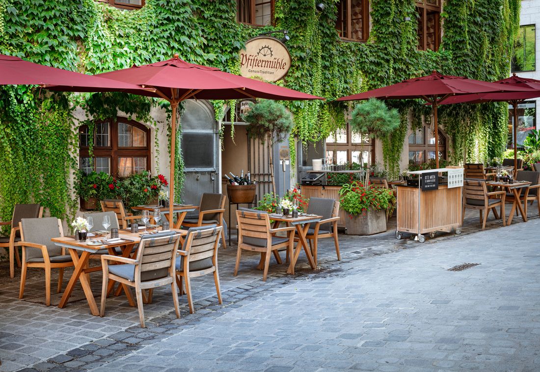 Außenbereich des Restaurants Pfistermühle mit gemütlicher Terrasse und grünem Fassadenbewuchs