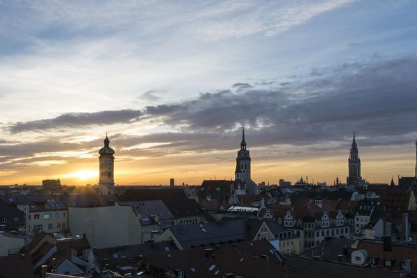 Die Skyline Münchens beim Sonnenaufgang mit dem Turm des alten und neuen Rathauses, des alten Peters, der Frauenkirche und der Heilig-Geiste Kirche.
