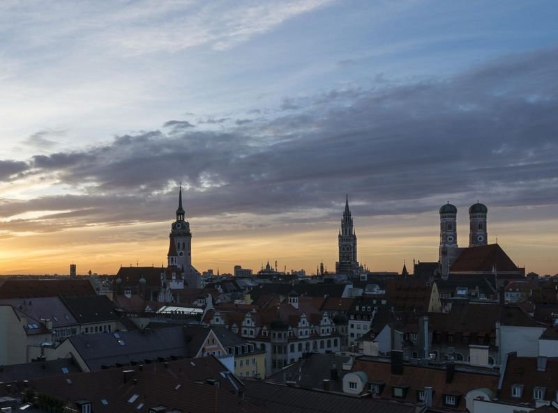 Die Skyline Münchens beim Sonnenaufgang mit dem Turm des alten und neuen Rathauses, des alten Peters, der Frauenkirche und der Heilig-Geiste Kirche.