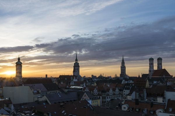 Die Skyline Münchens beim Sonnenaufgang mit dem Turm des alten und neuen Rathauses, des alten Peters, der Frauenkirche und der Heilig-Geiste Kirche.