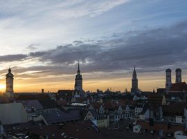 Die Skyline Münchens beim Sonnenaufgang mit dem Turm des alten und neuen Rathauses, des alten Peters, der Frauenkirche und der Heilig-Geiste Kirche.