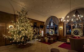 Weihnachtlich geschmückte Lobby des Platzl Hotel in München mit beleuchtetem Tannenbaum 