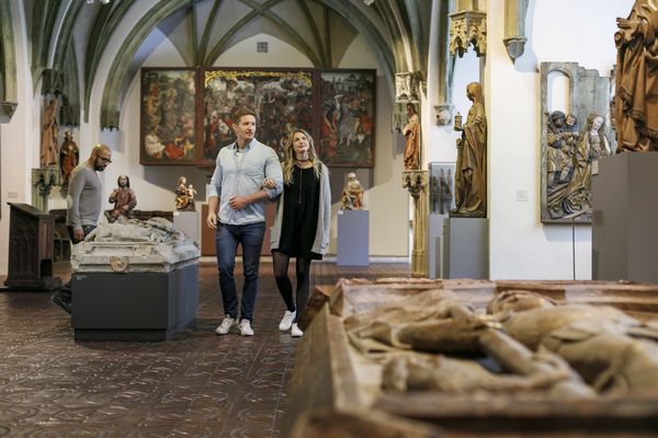 Pärchen besucht das Bayerische Nationalmuseum in München und betrachtet kunstvolle Skulpturen und Gemälde aus verschiedenen Epochen.