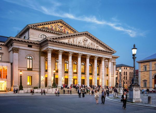 Bavarian State Opera in the evening with pedestrians in front.