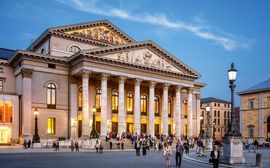 Bavarian State Opera in the evening with pedestrians in front.