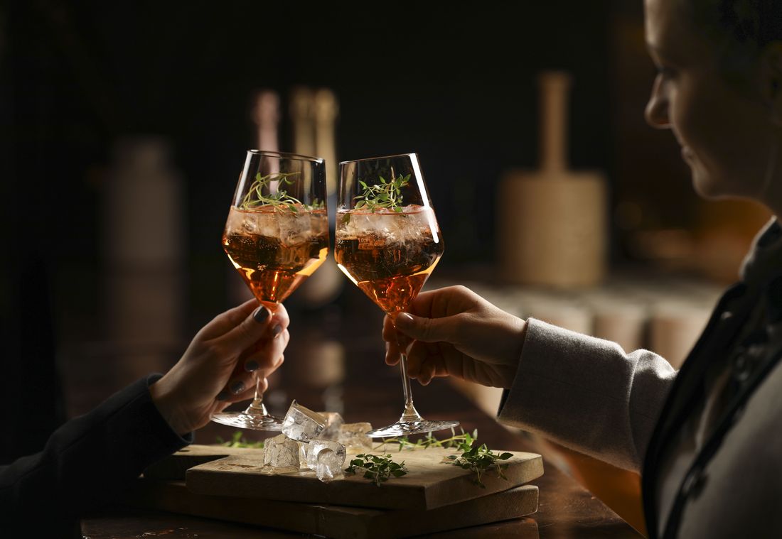 Zwei Gäste genießen den Abend an der Hotelbar und stoßen mit verfeinerten Cocktails an