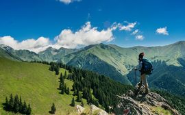 A hiker is standing on a rock with a beautiful landscape in front of him